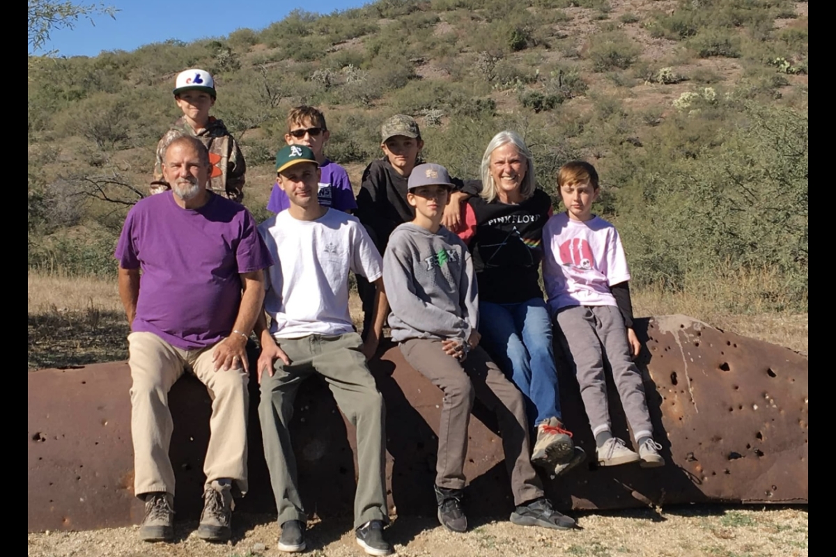 Man posing with his grandchildren in an outdoor setting.