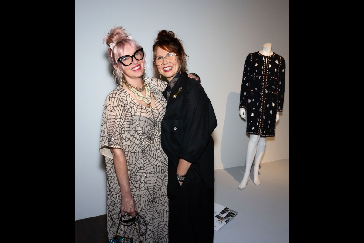 Two women pose near a manikin with a black garment.