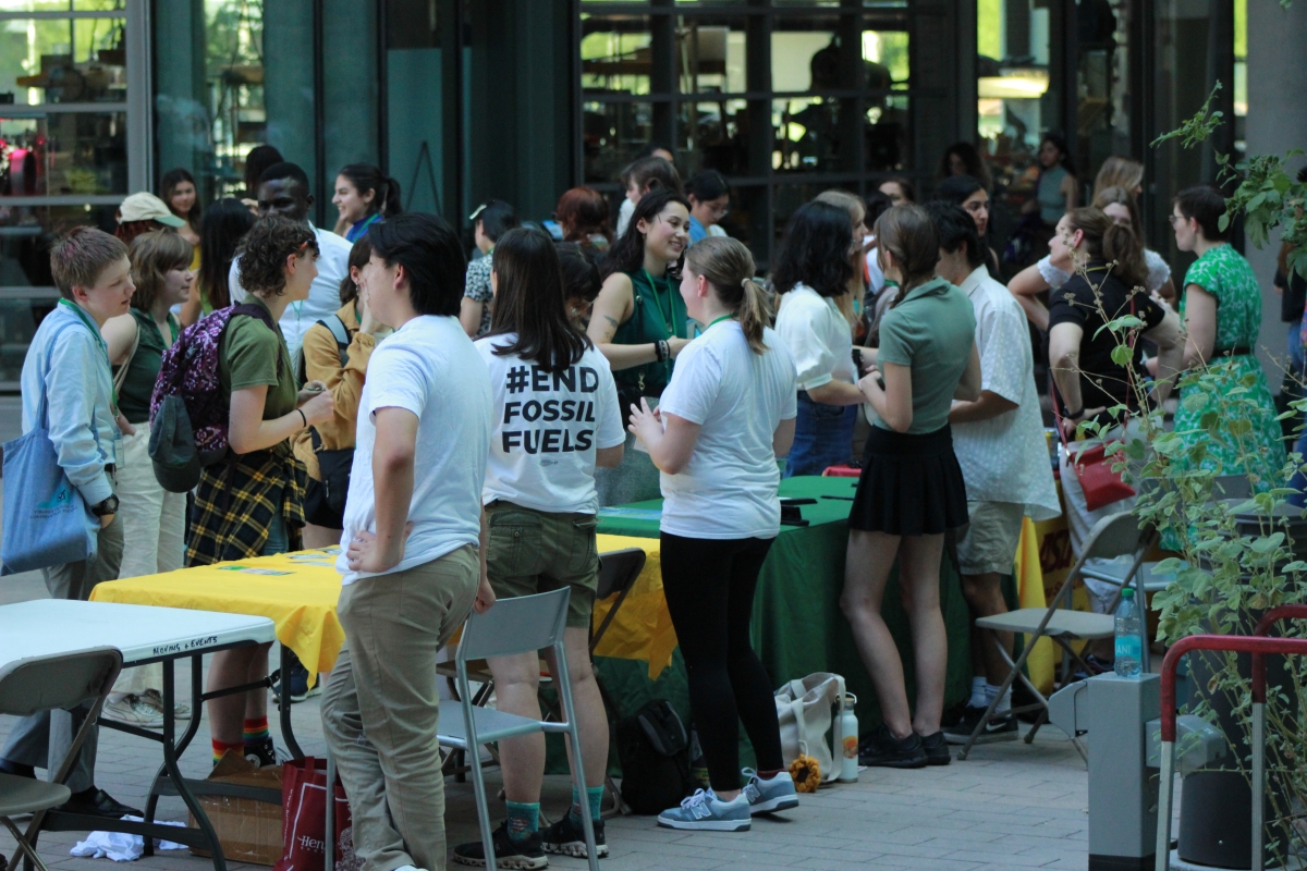 A crowd of youth delegates gather in an atrium around tables.