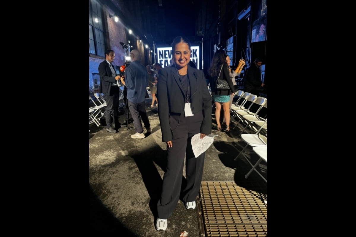 Woman in a black pantsuit standing at the end of a runway.