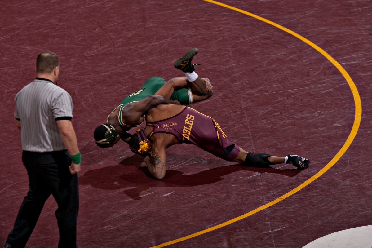 Two men wrestling on maroon mat