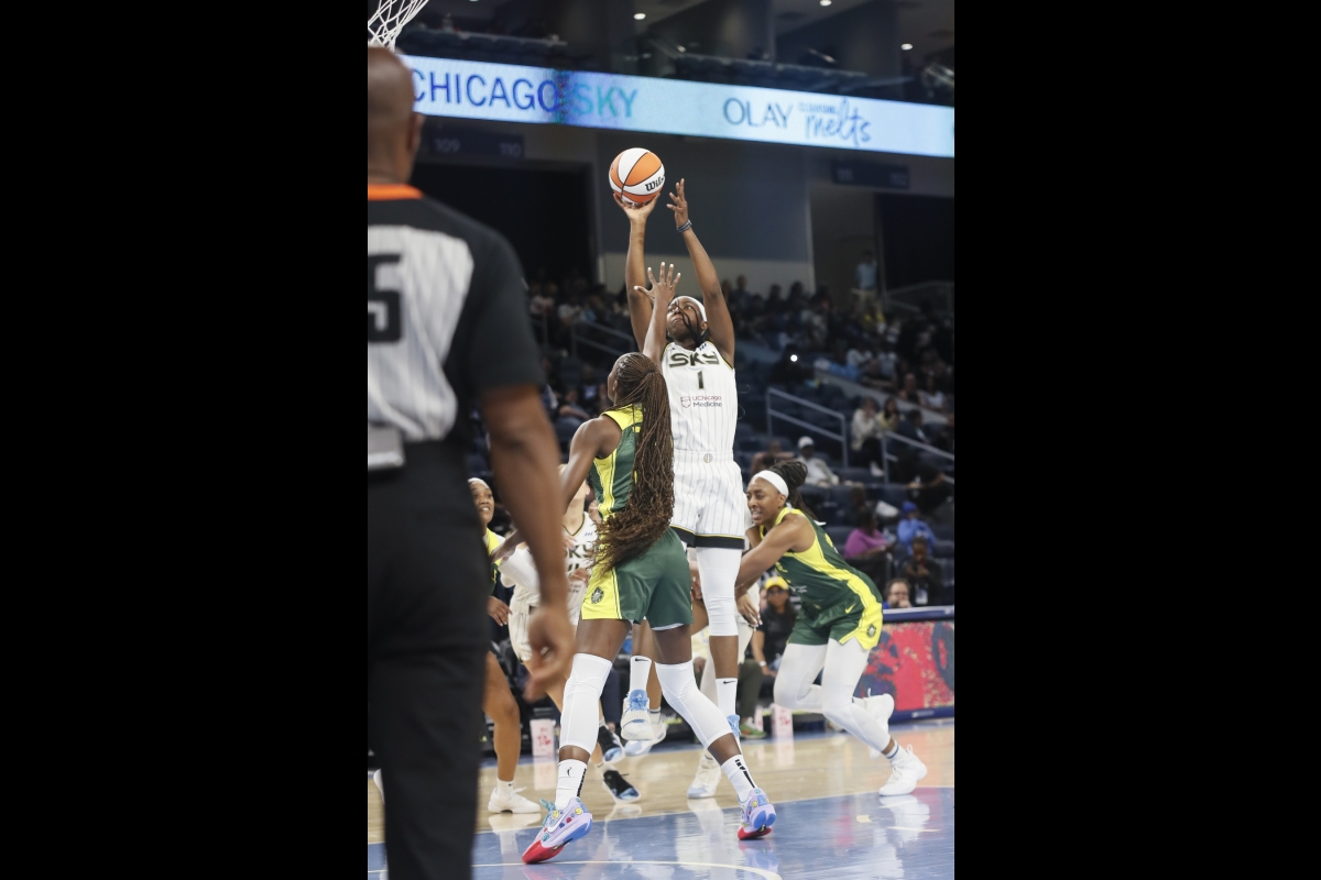 A woman shoots a basketball over the heads of her competitors