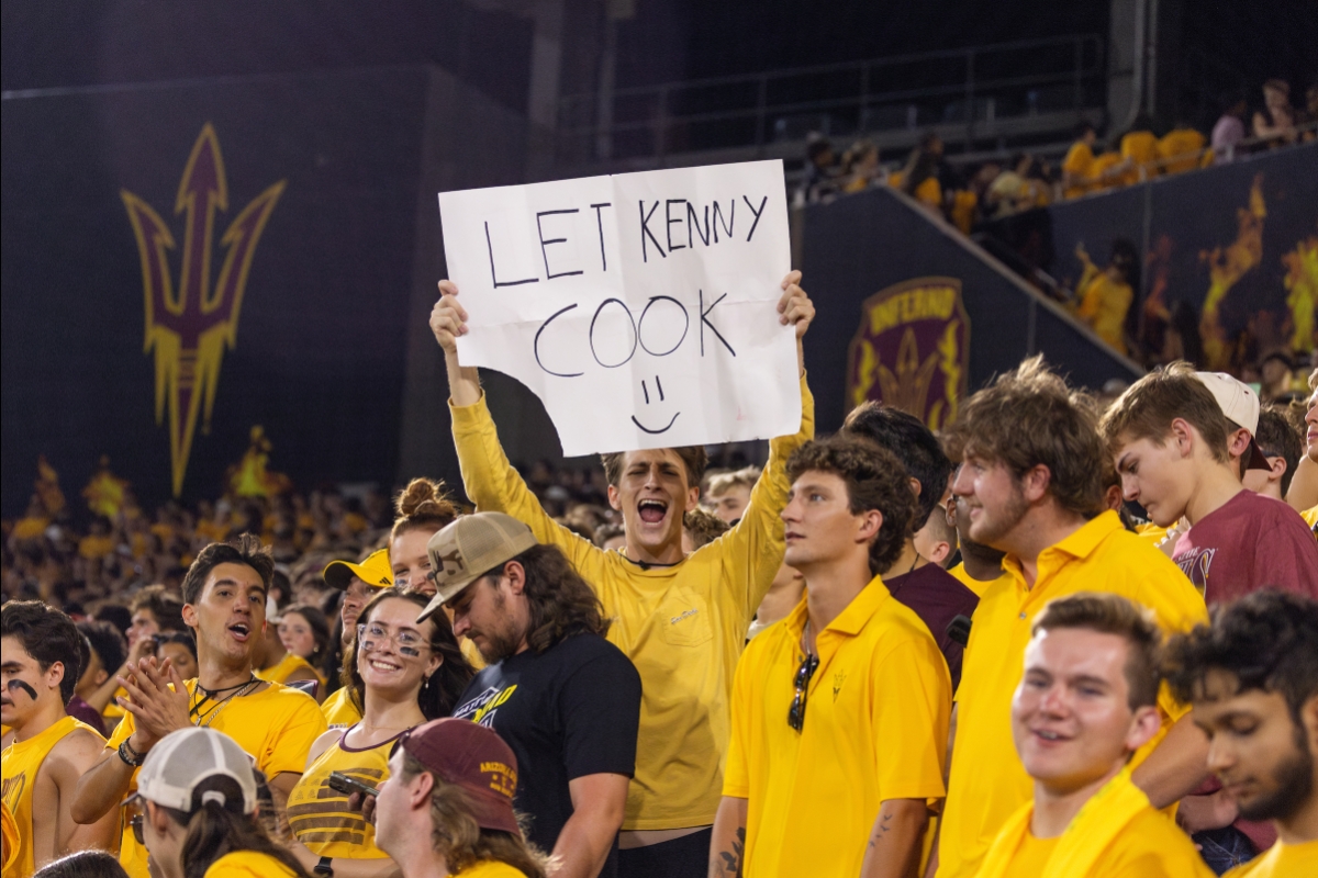 Fan in ASU stands holding sign that says Let Kenny Cook