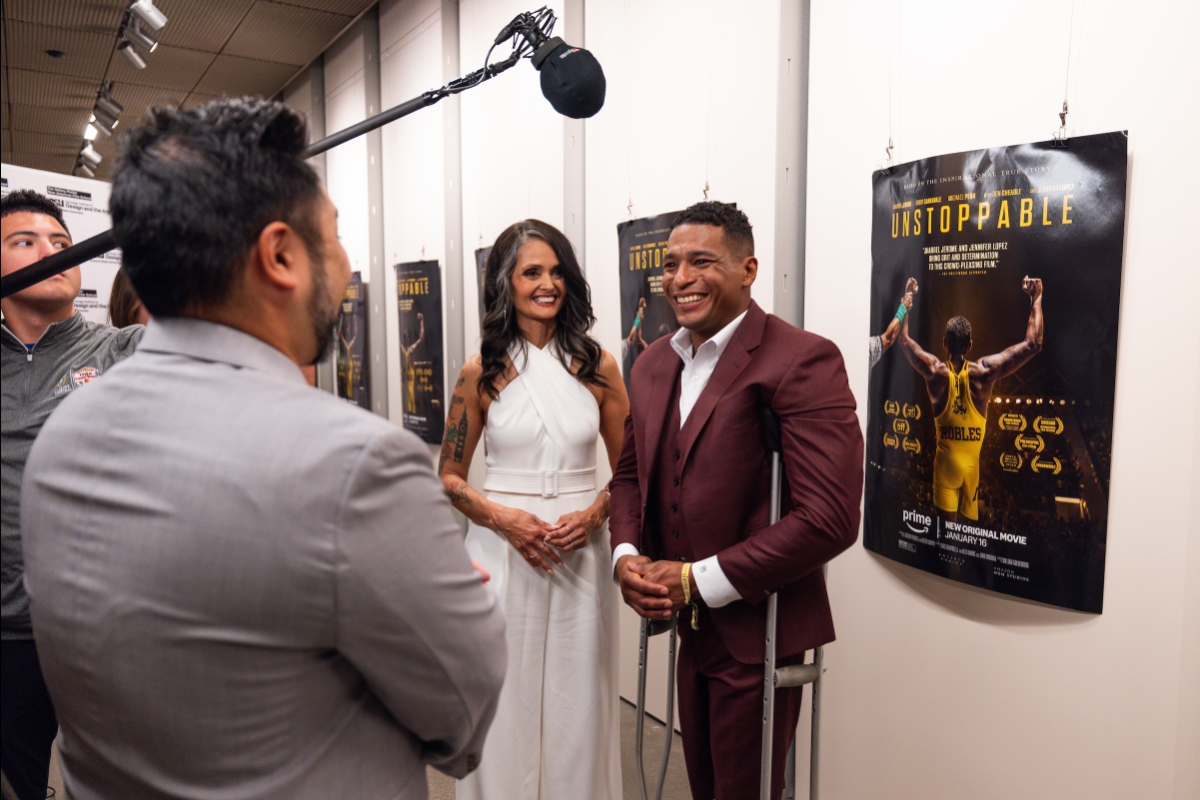 A man and a woman smile as they are interviewed on camera