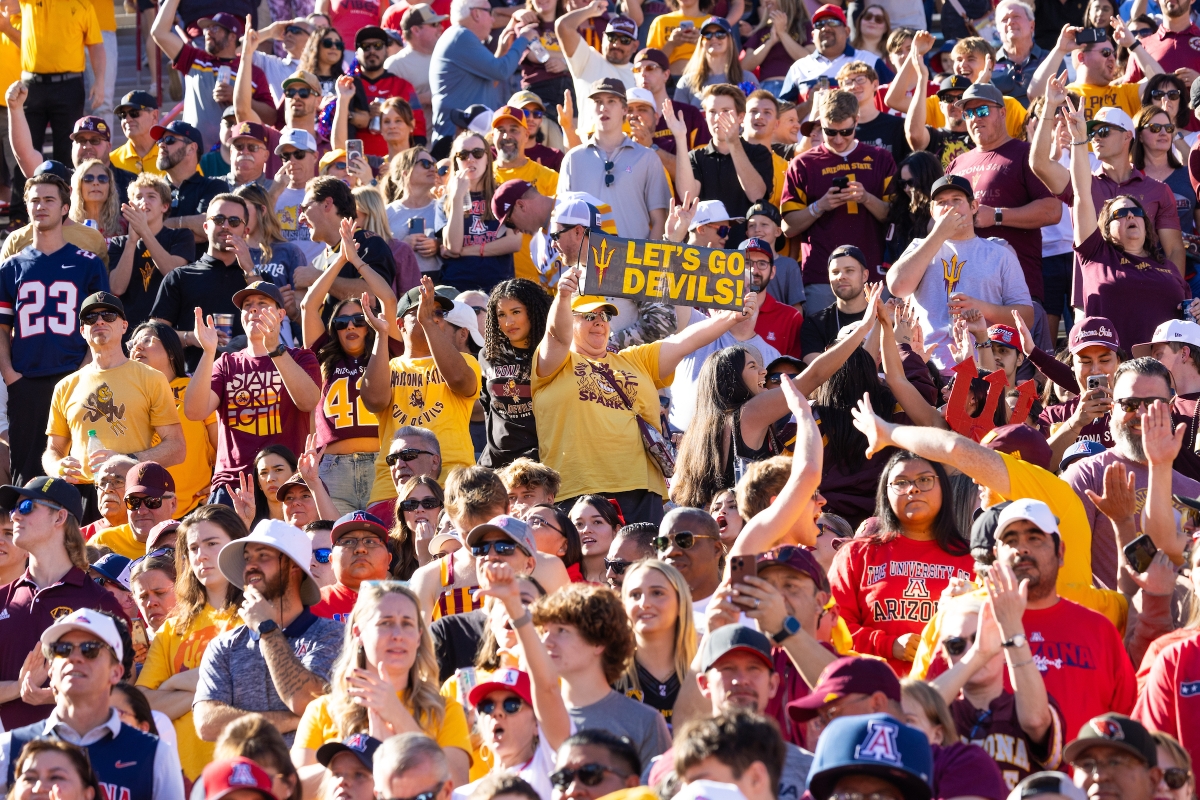 A Sun Devil fan holds a sign that says Let's Go Devils in a sea of ASU and UA fans