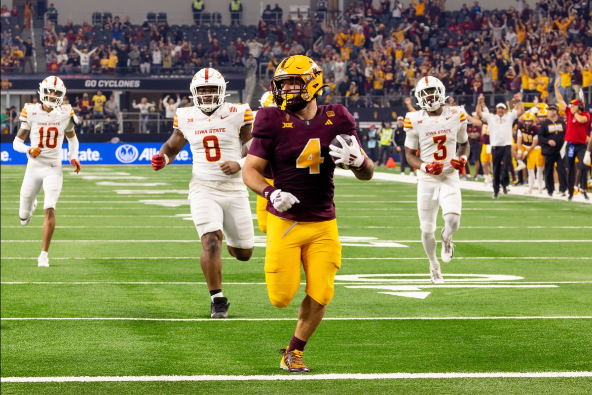 ASU football player runs across the field with three Iowa players chasing behind him