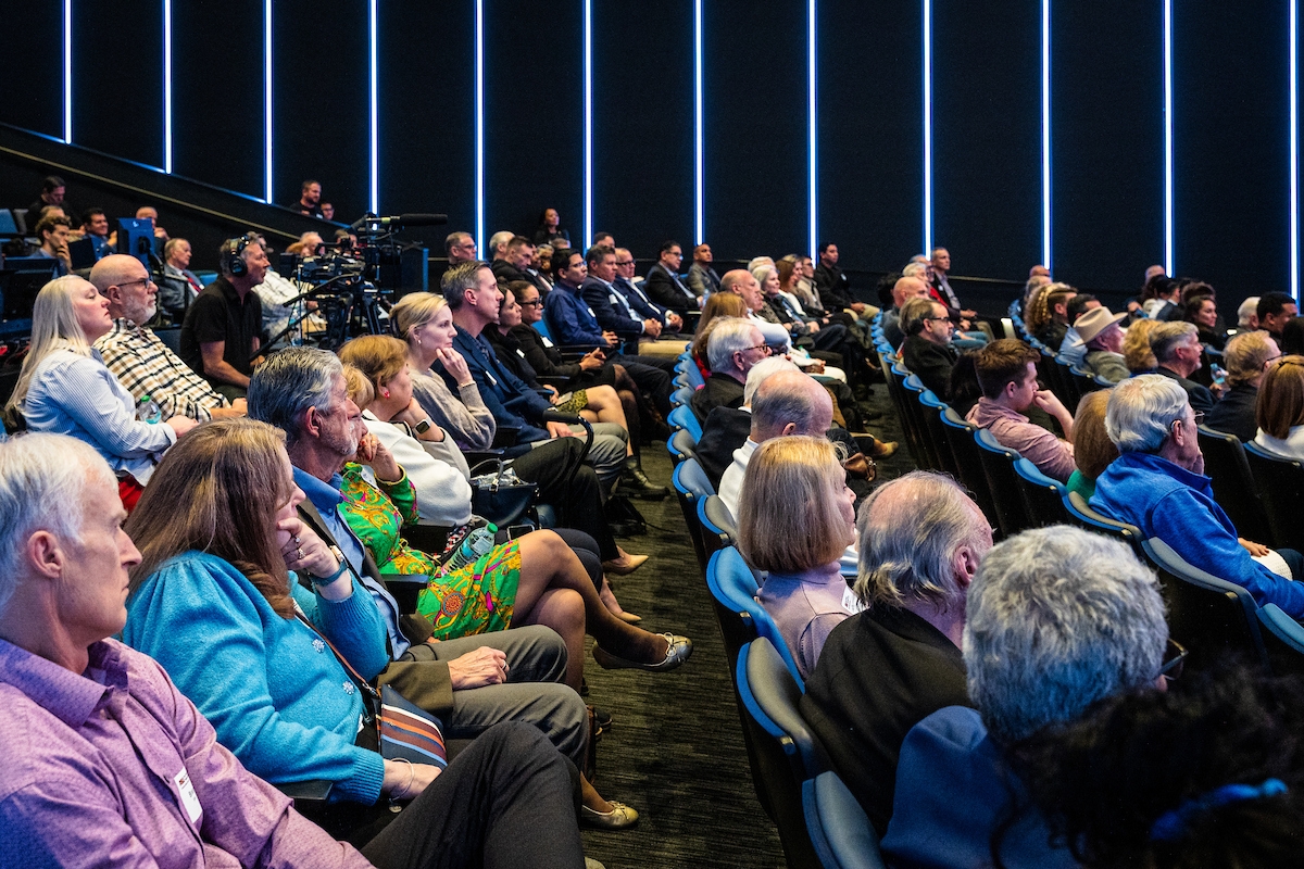 People seated in an auditorium listening to an unseen speaker.