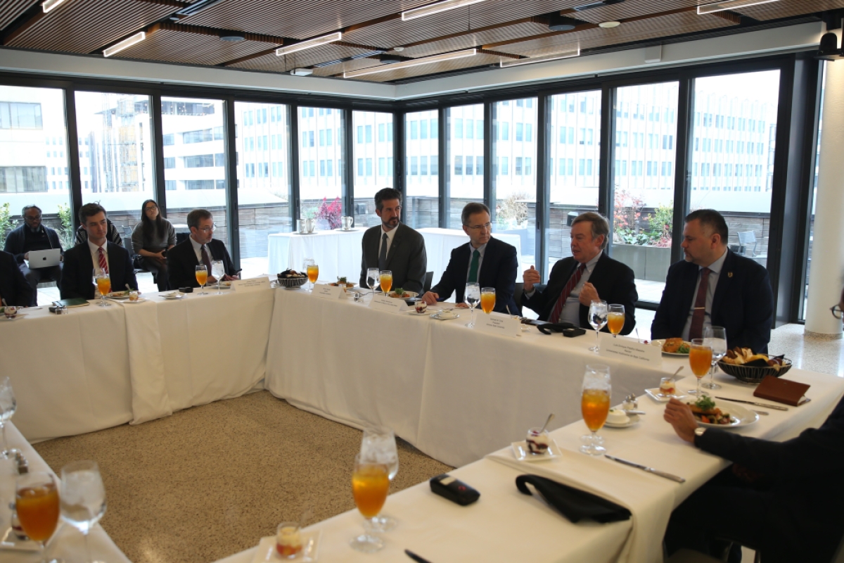 Michael Crow speaks to an audience seated around a large table