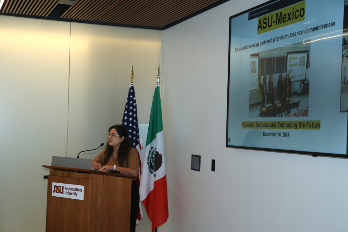 Woman standing behind a podium speaking to an unseen audience.