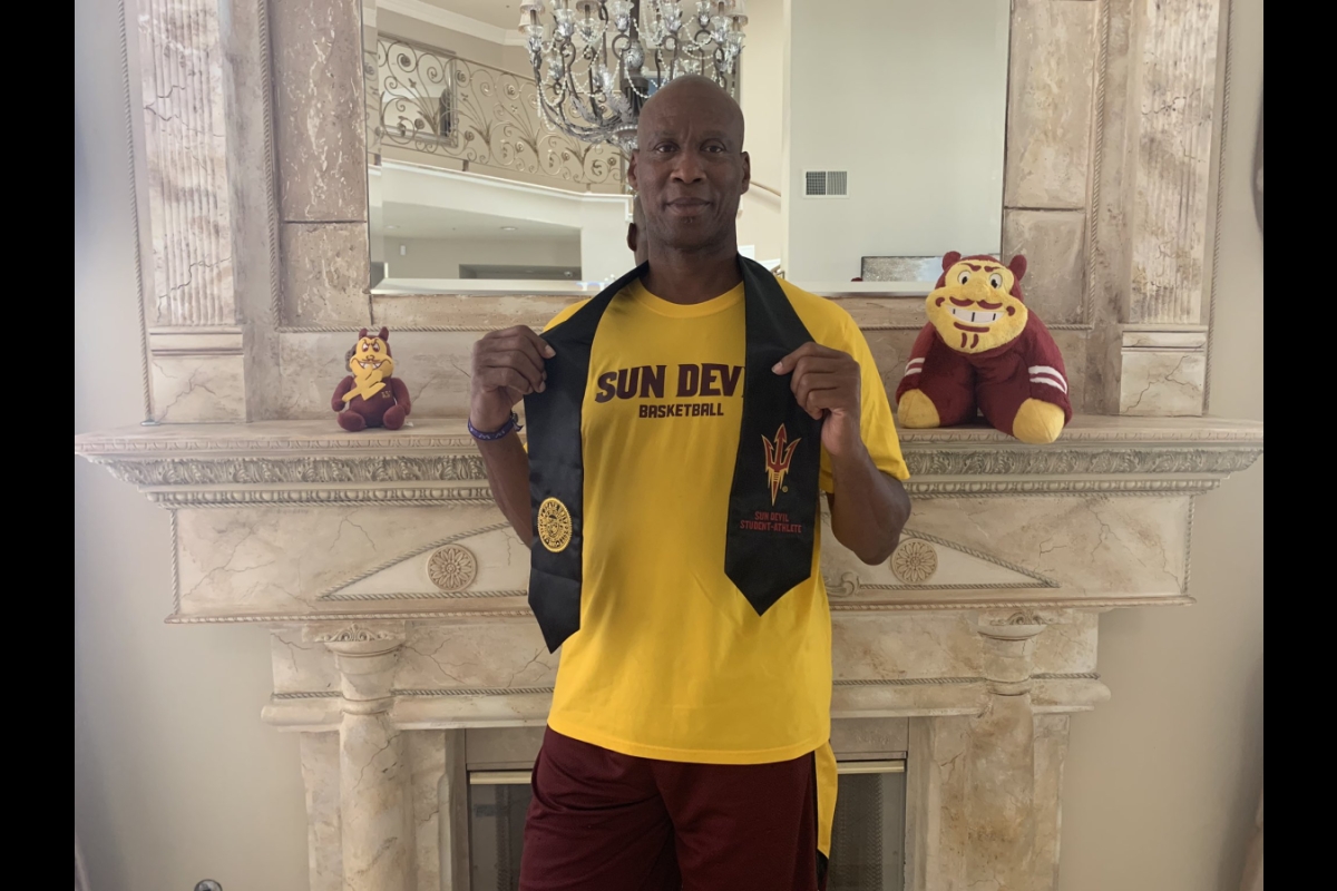 Former ASU basketball player Byron Scott wears a gold ASU T-shirt and a black graduation stole.