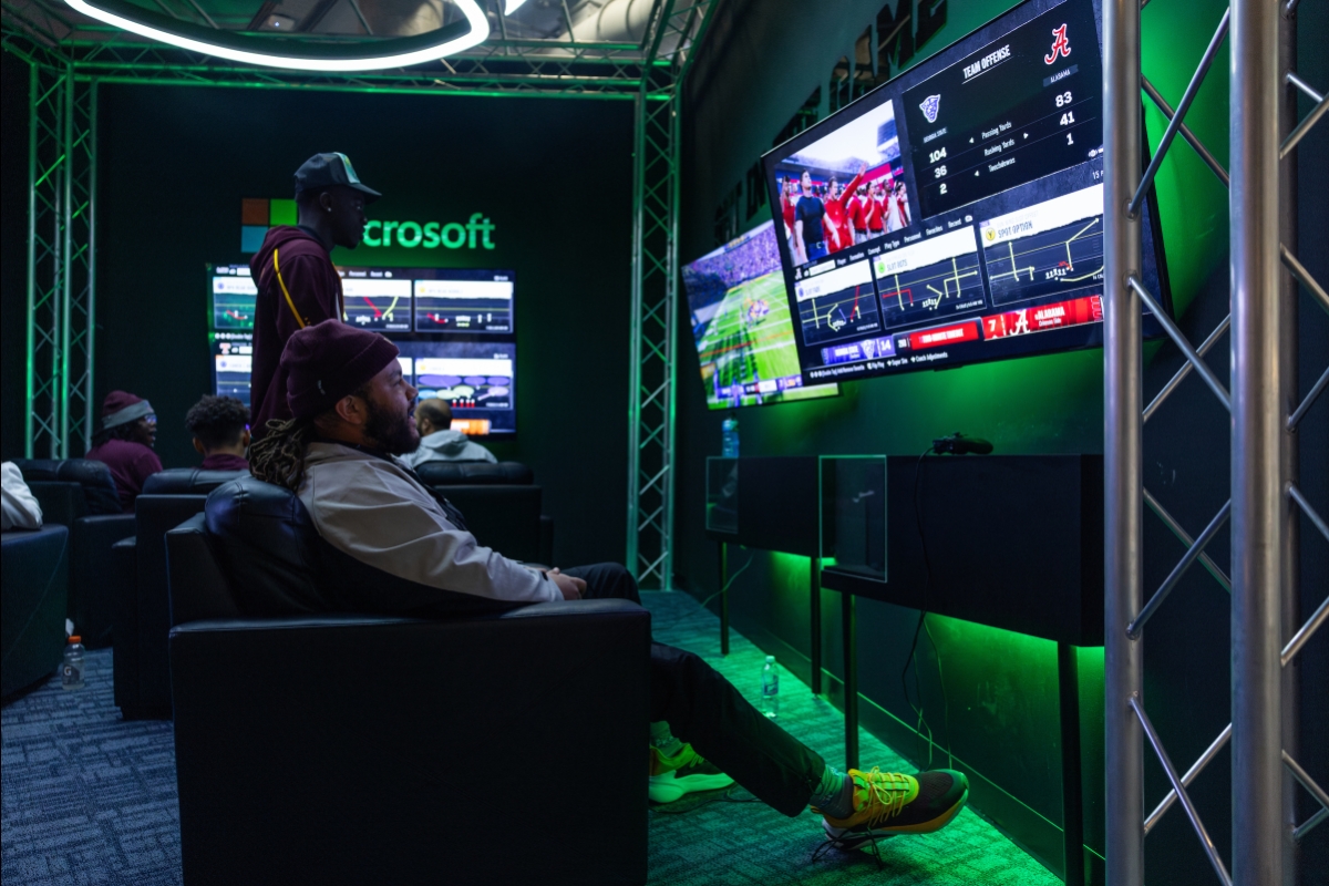 College players sit in a green-lit esports lounge looking at screens