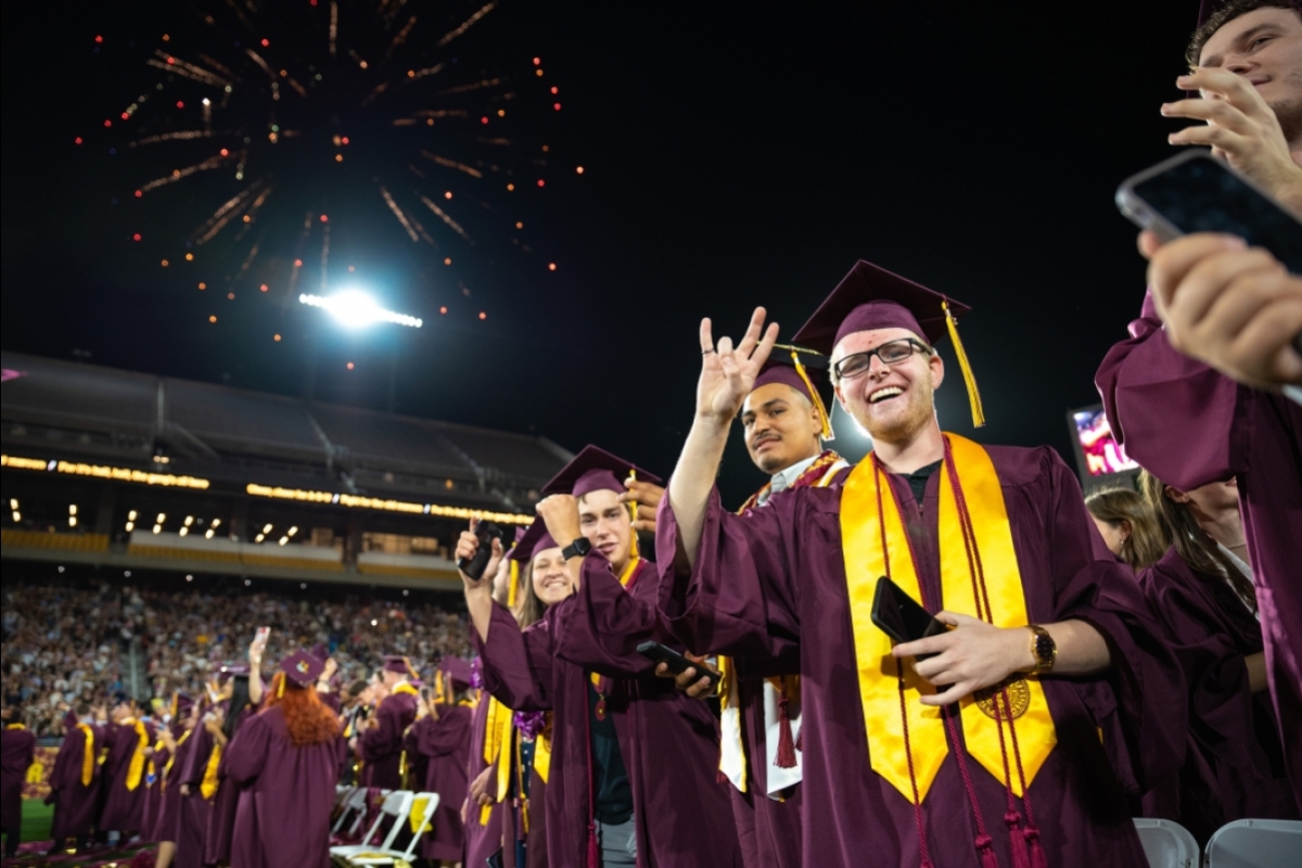 Graduates cheer as fireworks go off in the sky