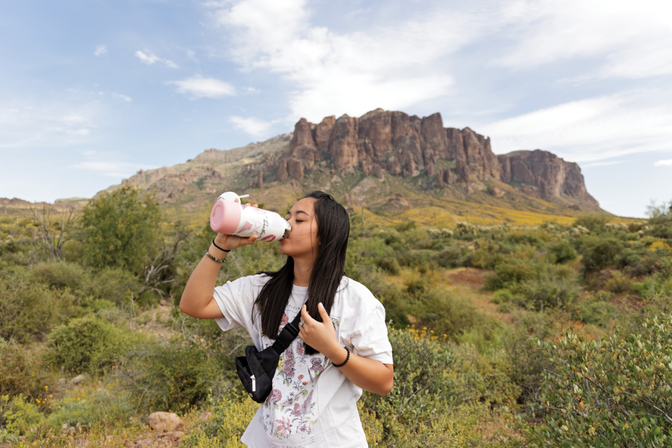 Woman drinking out of a reusable water bottle on a hike