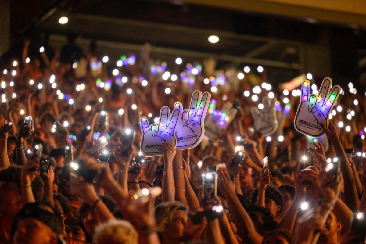 Group of hands raised at stadium holding phones with the flashlights on