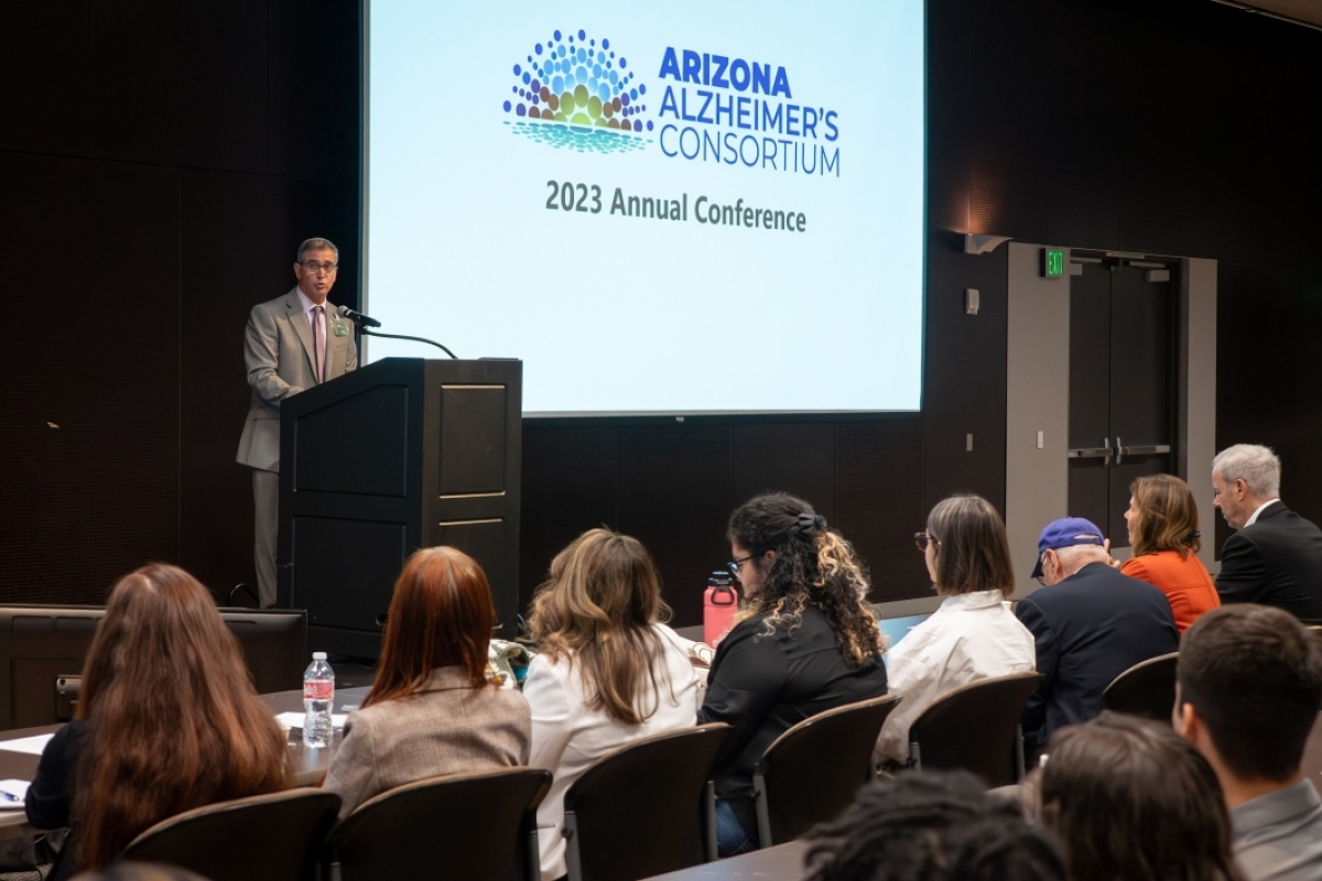 Dr. William Faubion Jr. delivers opening remarks at a podium the Arizona Alzheimer's Consortium logo is visible behind him
