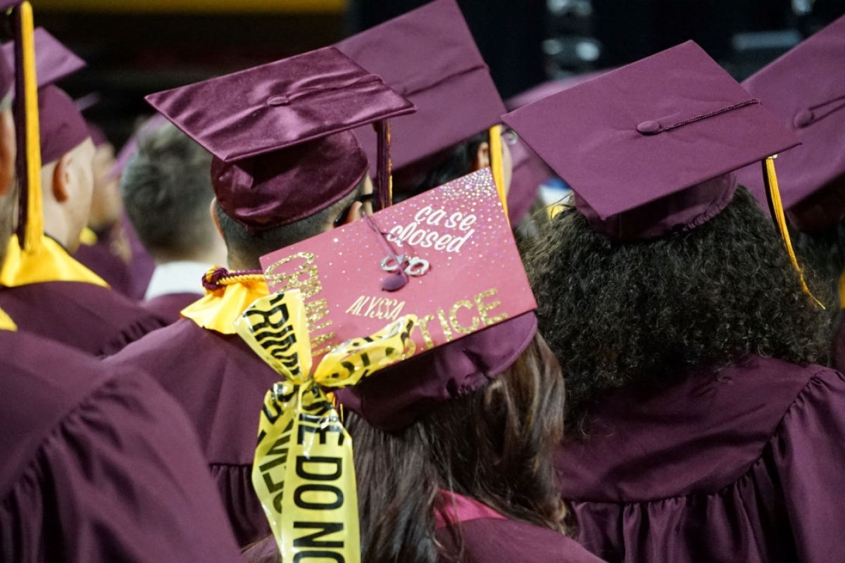 A group of people facing away from the camera wearing graduation caps.