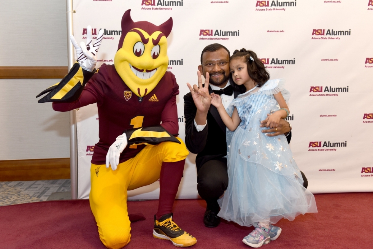 Man and young girl posing with ASU mascot Sparky the Sun Devil.