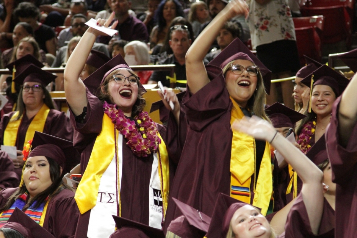 Graduates waving enthusiastically in a crowd.