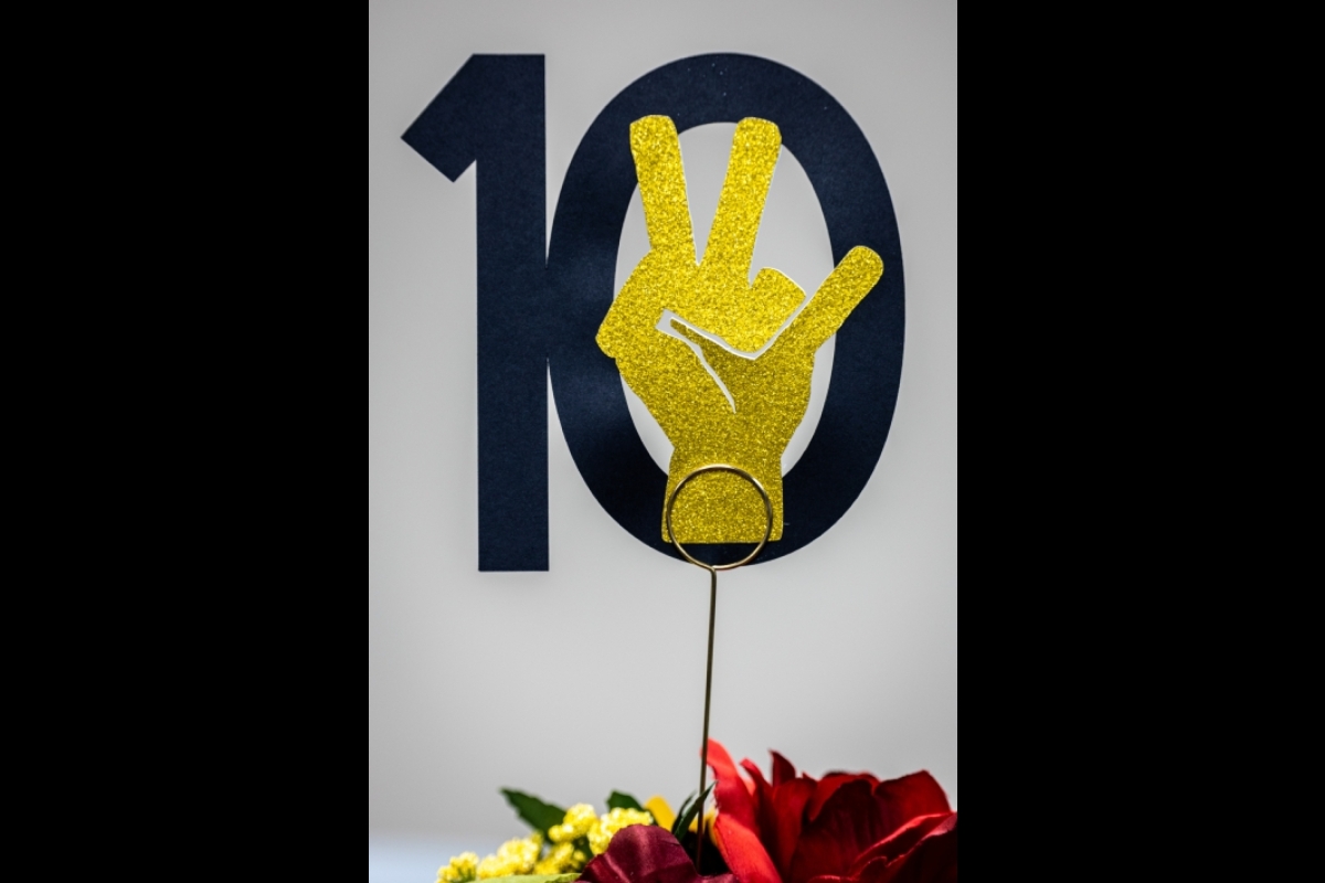 Paper cutout of the ASU pitchfork hand symbol with the number 10 on a table at an event.