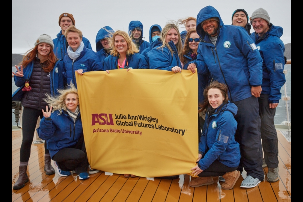 Group of ASU students on a boat pose with a sign that reads: ASU Julie Ann Wrigley Global Futures Laboratory.