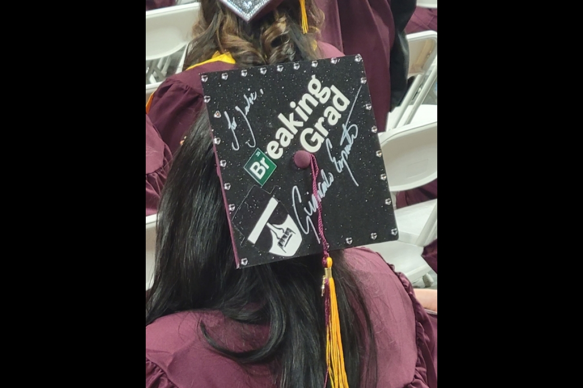 A graduate wears a decorated mortarboard that reads 