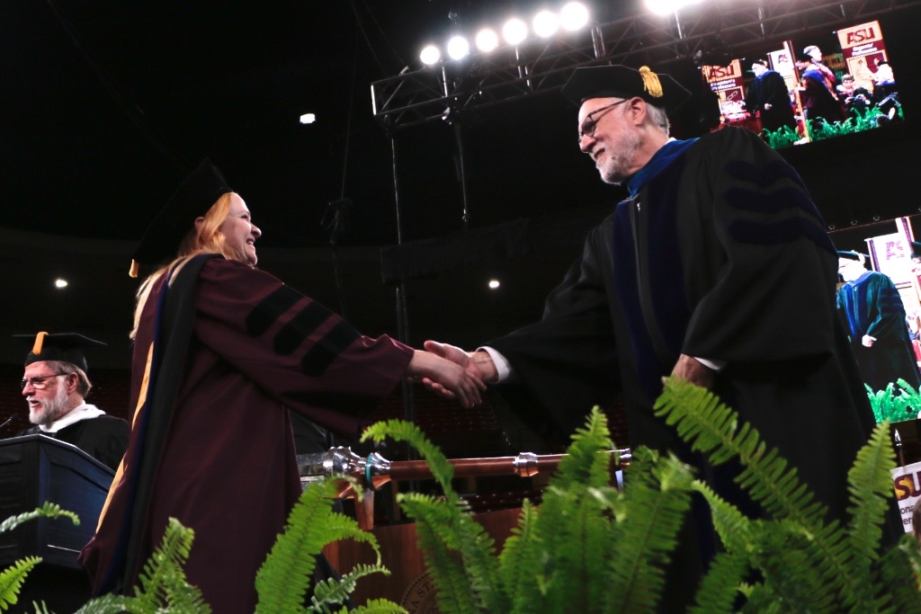 Wendy Caldwell shakes hands with University Provost Mark Searle during ASU Graduate Commencement