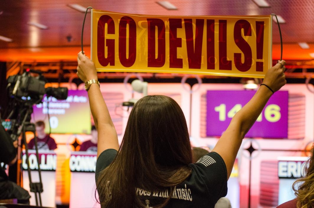 student holding up a Sun Devil banner