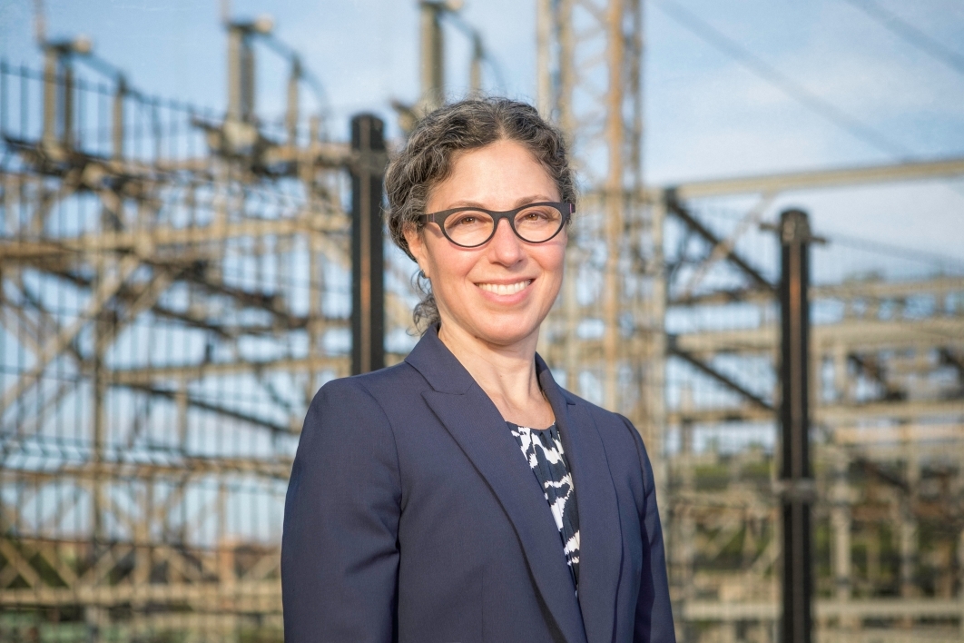 Portrait of University of Michigan Professor Alexandra Klass standing in front of a power grid system.