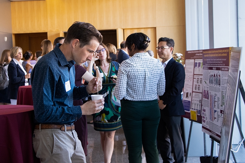 Stephen Schaefer studies a poster while stirring his coffee at the ARCS Showcase reception