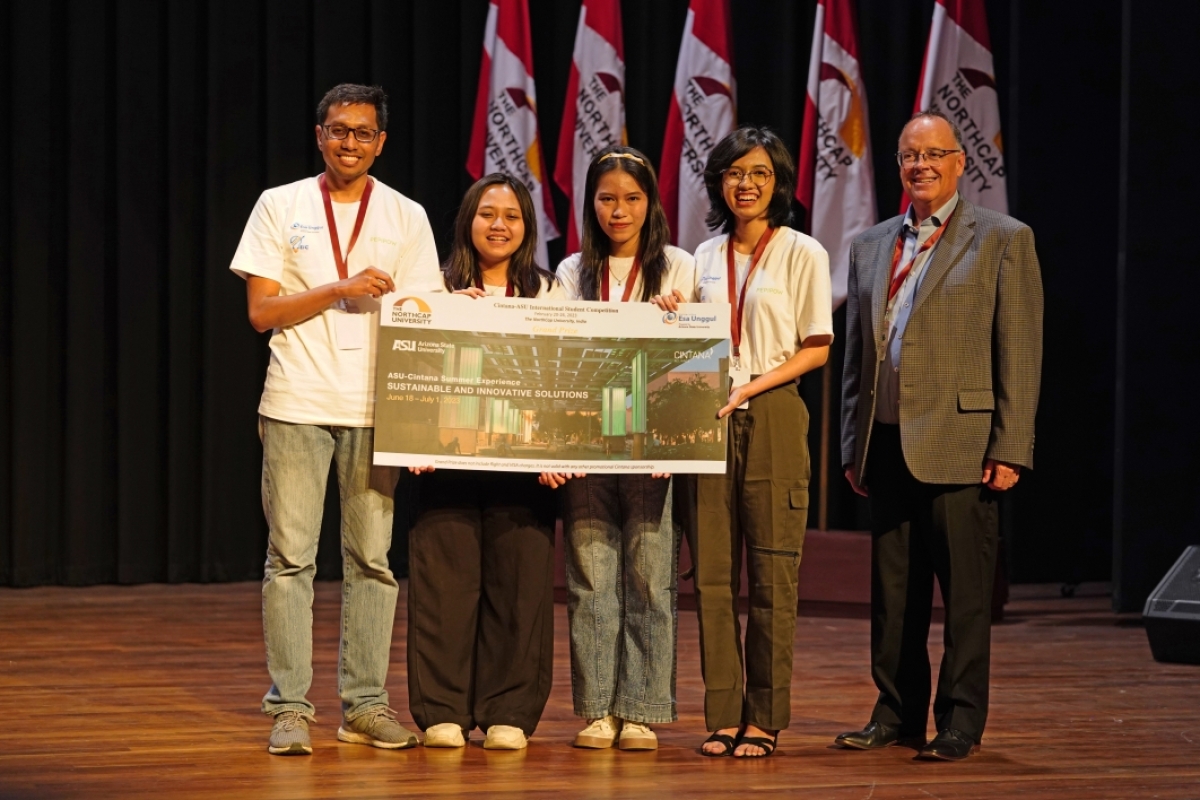 Winning team of students pose on stage with certificate