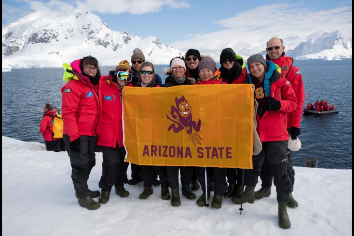 Group of ASU students holding an ASU flag on an iceberg in Antarctica