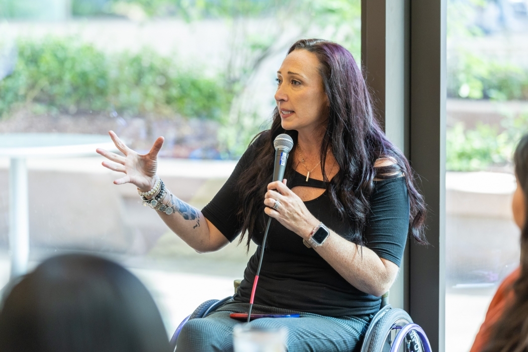 Woman seated in a wheelchair speaking into a microphone.