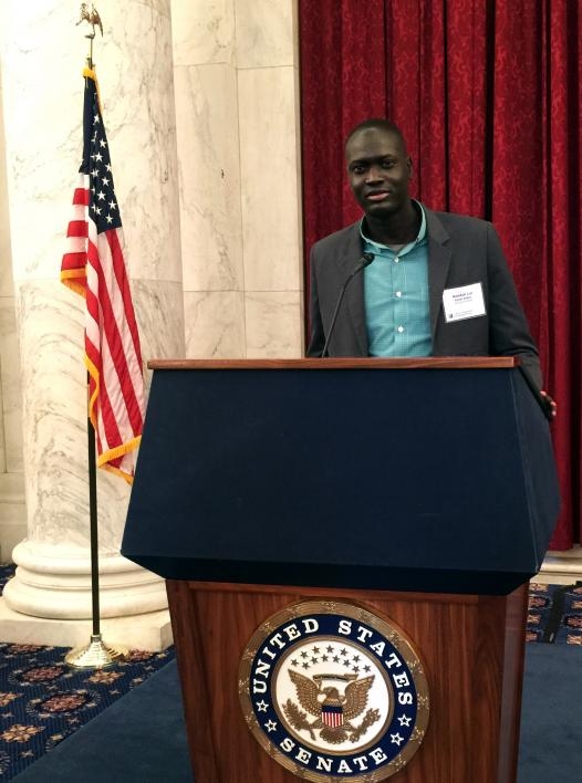 Bandak Lul stands behind a United States Senate podium.
