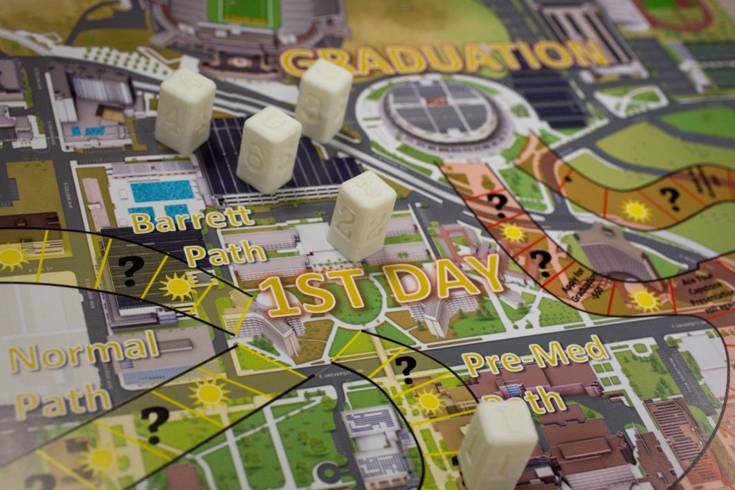 The pieces of a student-created campus board game are displayed on a table.