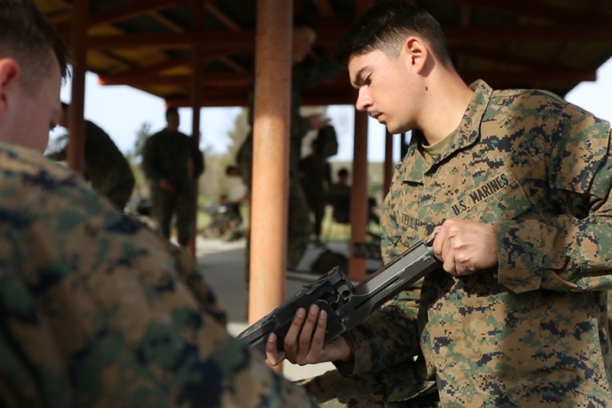 Man wearing military fatigues holding a machine gun.