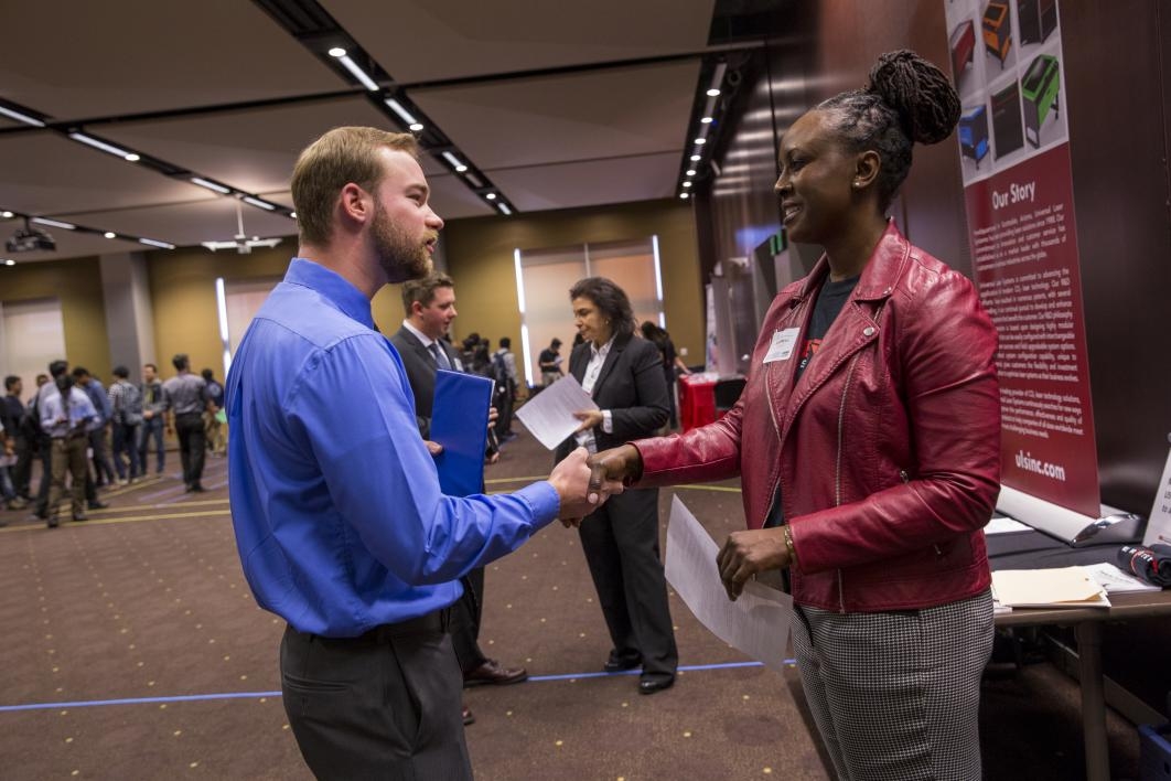 woman shaking hands with student at career fair