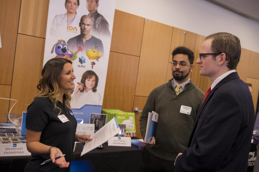 woman talking to two students at career fair
