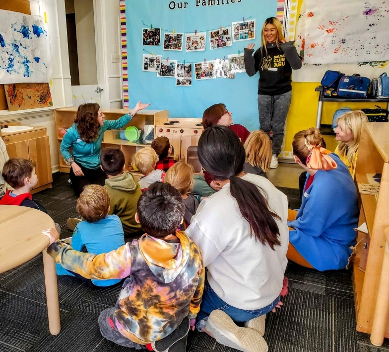 An adult gives a presentation to a group of children sitting on the floor.
