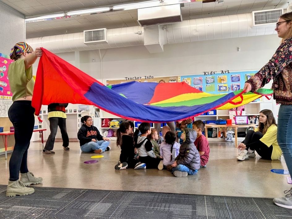 Adults and children play with a parachute.