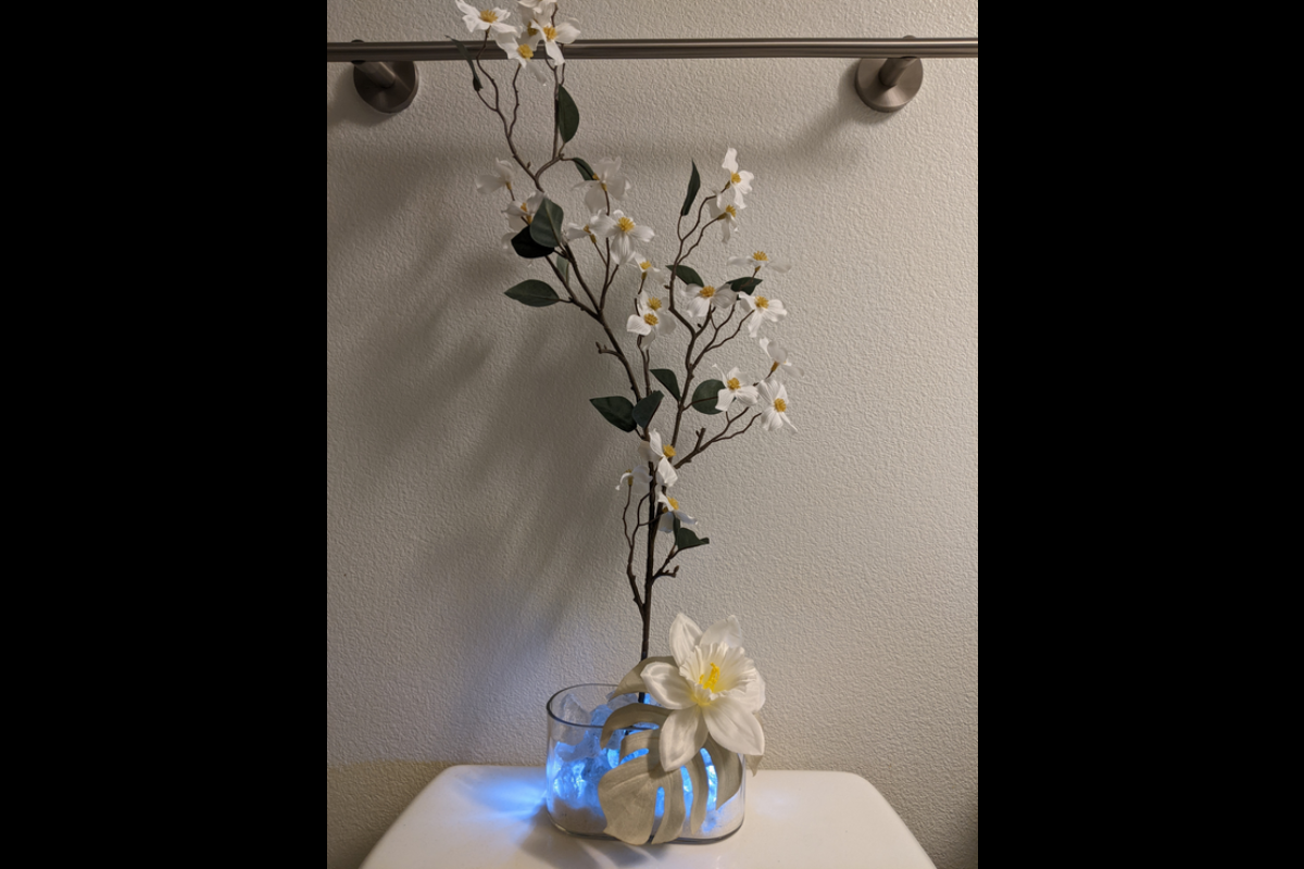 Faux plant in a vase in a bathroom emitting a motion sensor light.
