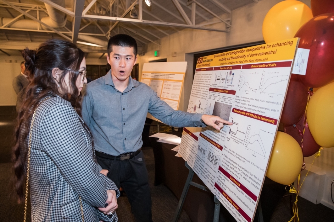 College of Health Solutions' Qiaobin Hu talks about research with a visitor.