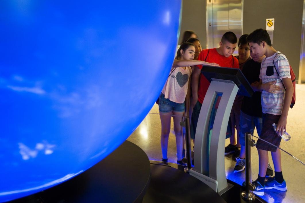 Students with the Conexiones program look at an interactive globe display at ASU