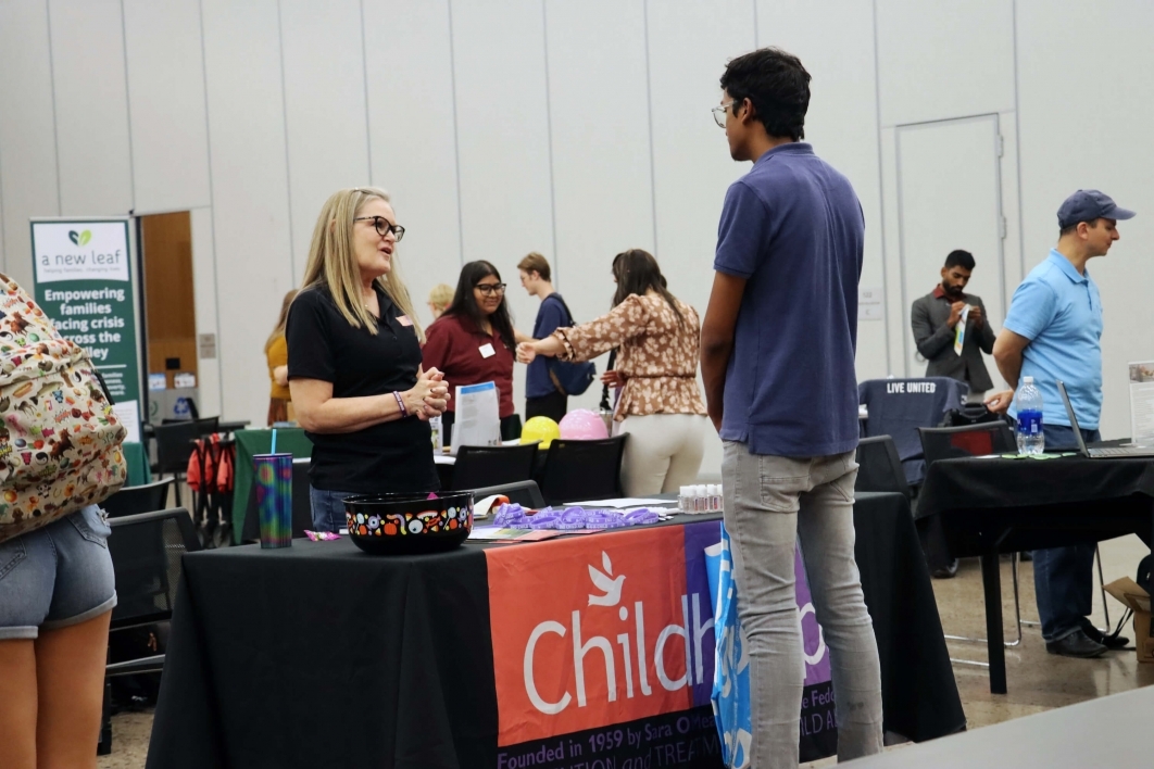 student speaking to a woman at a table at a networking event