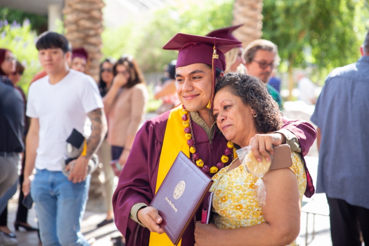 A graduate and family member embrace and pose for a photo