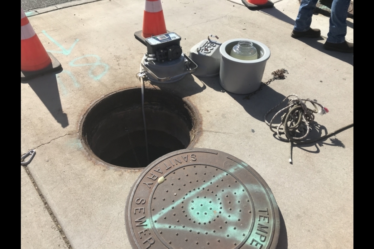 Open manhole on a city sidewalk.
