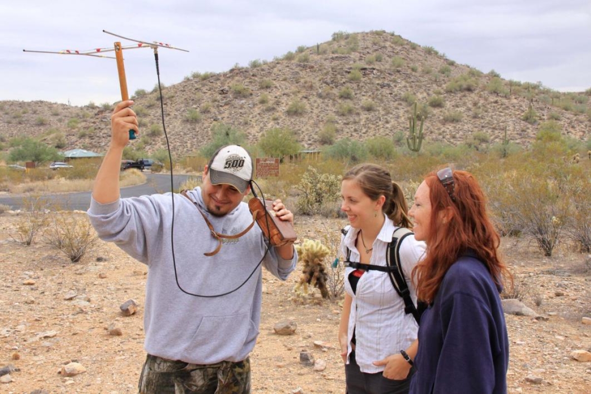 people using instrument to listen to animals in desert