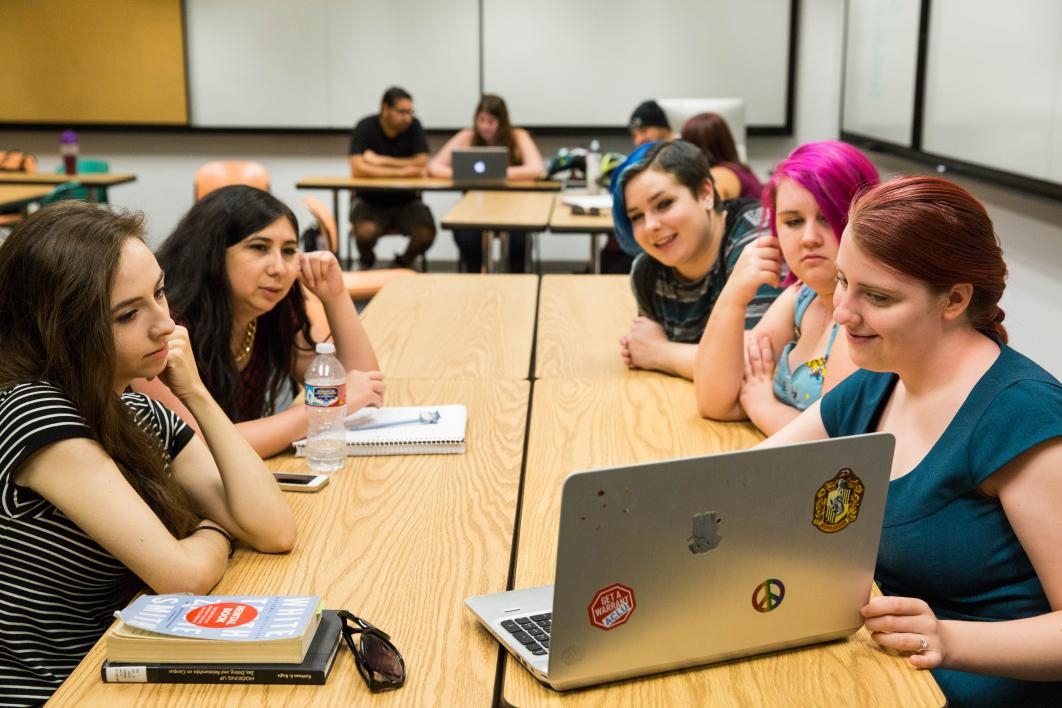 group of students looking at laptop in classroom