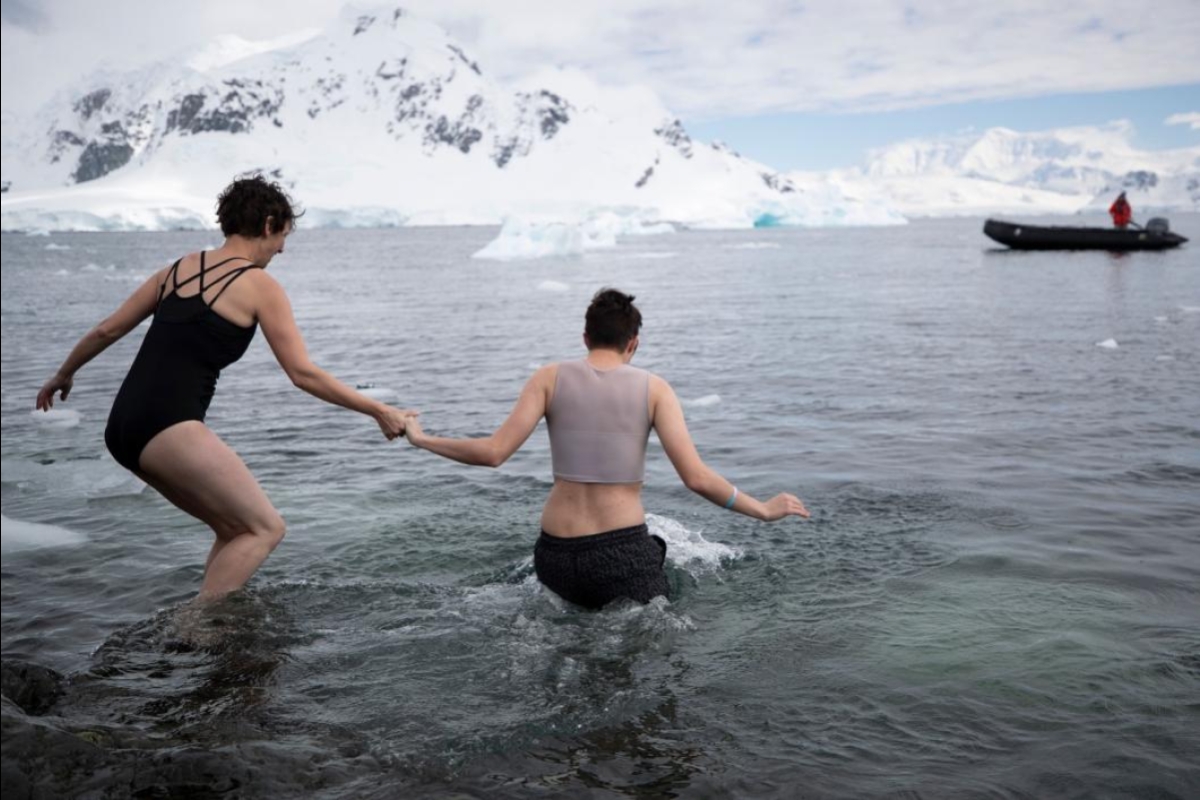 Professor Diana Bowman and student Oliver Pemberton jump into the Antarctic water