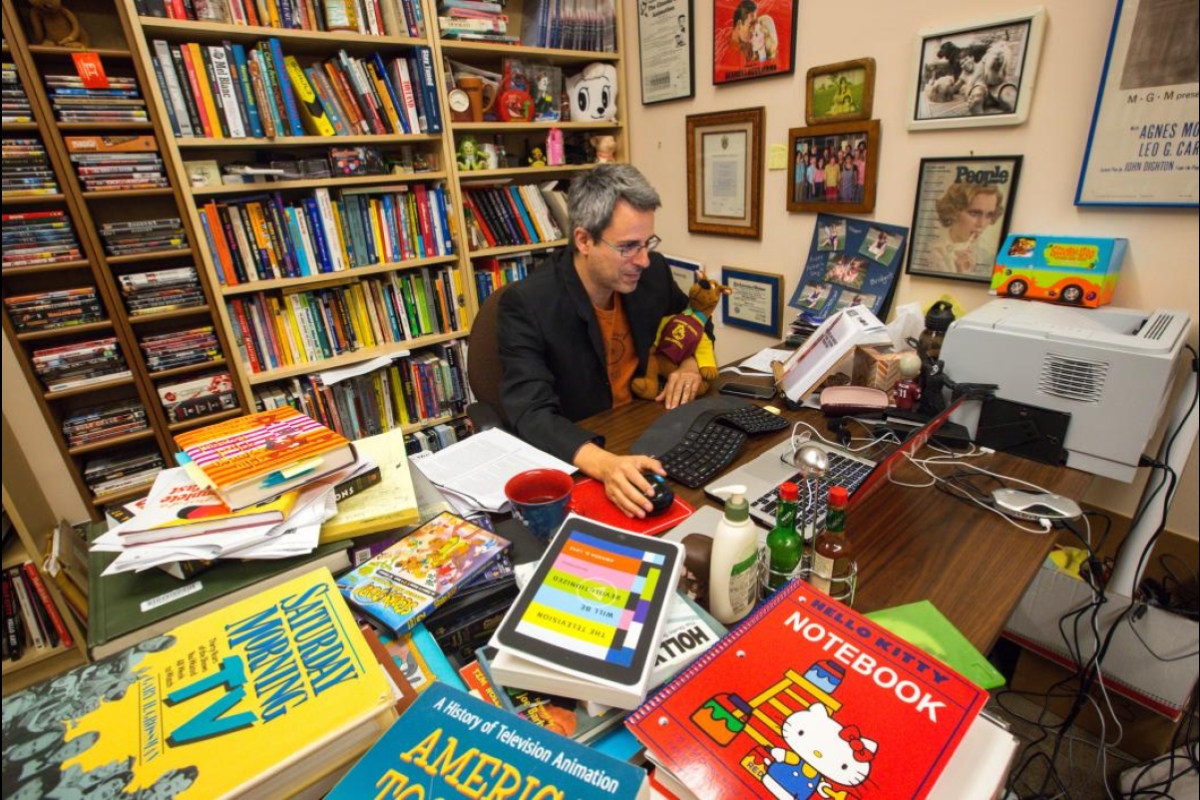 Kevin Sandler surrounded by books in his small office
