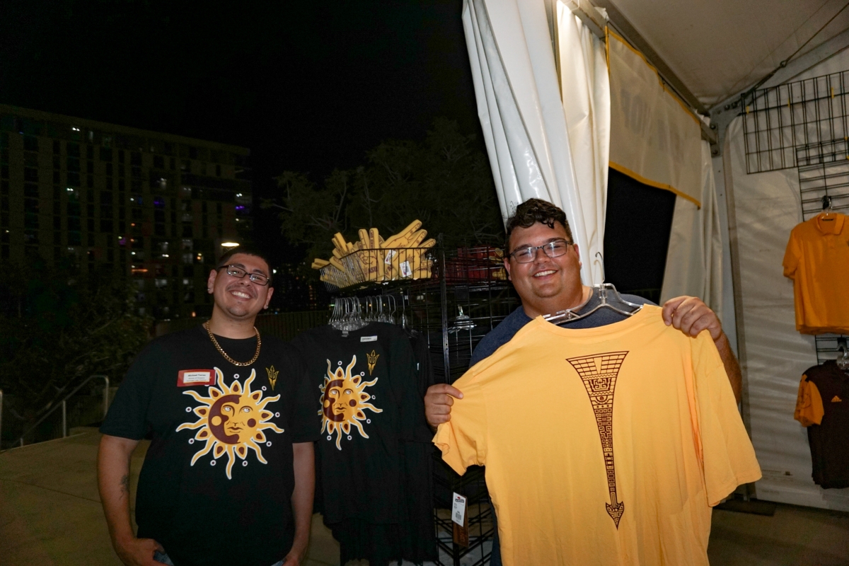 Michael Torres (left) and Justin Gilbert (right) pose next to shirts with their logos at a pop-up shop at Sun Devil Stadium.
